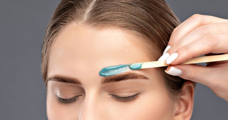 Woman receiving eyebrow wax application for beauty treatment