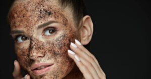 Woman with exfoliating coffee scrub on facial skin