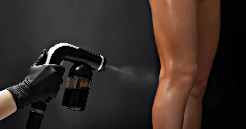 Professional spray tan application on woman's legs in salon