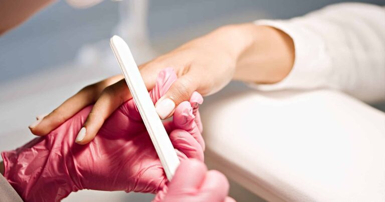 Manicurist wearing gloves filing nails in a professional setting