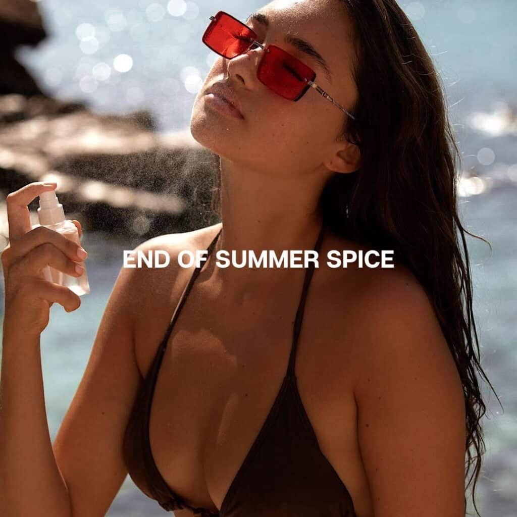 Woman in red sunglasses spraying mist by the ocean