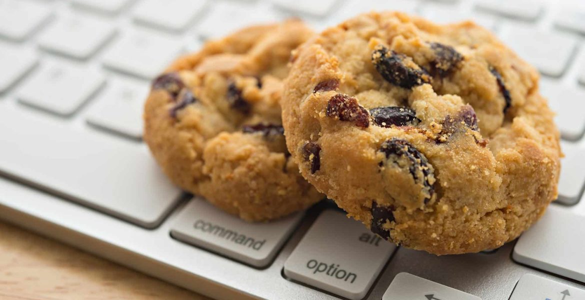 Chocolate chip cookies on a silver computer keyboard, symbolizing internet cookies