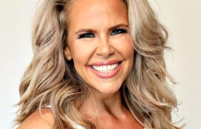 Smiling woman with long blonde hair wearing a white top