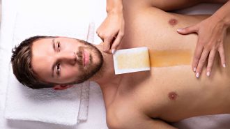 Man receiving chest hair removal with waxing strip