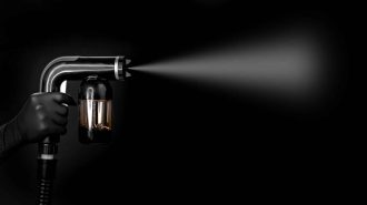 Handheld paint sprayer spraying mist on black background